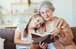 Happy family grandmother reading to granddaughter book at home