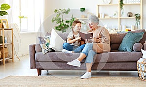 Happy family grandmother reading to granddaughter book at home