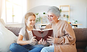 Happy family grandmother reading to granddaughter book at home