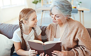 Happy family grandmother reading to granddaughter book at home