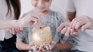 happy family hands holding piggy bank. kid and parents put coins into piggy bank