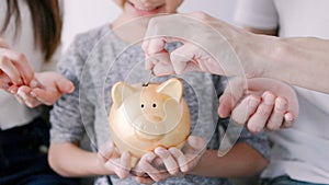 Happy family hands holding piggy bank. kid and parents put coins into piggy bank