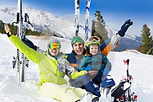 Happy family with hands up on snow after skiing