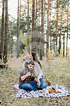 Happy family, handsome father, attractive mother and joyful little child toddler son, having fun together in autumn