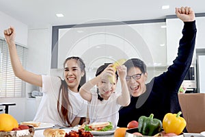 Happy family has meal in dining room. Mother father kid daughter sit at dining table, have fun during breakfast or lunch. Cheerful