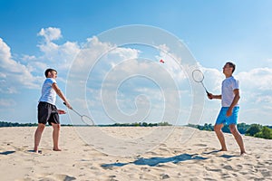 Happy family have fun playing beach badminton on summer vacation. Family outdoor sports games. Active healthy lifestyle concept