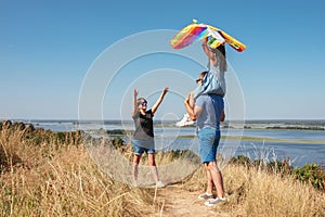 Happy family have fun playing with a kite in nature. The child sits on the shoulders of his father.