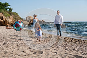 Happy family have a rest playing ball near sea