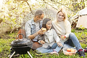 Happy family having a barbecue in their garden in spring. Leisure, food, family and holidays concept.