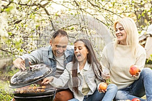 Happy family having a barbecue in their garden in spring. Leisure, food, family and holidays concept.