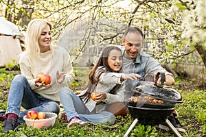 Happy family having a barbecue in their garden in spring. Leisure, food, family and holidays concept.
