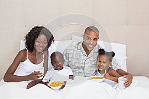 Happy family having breakfast in bed together in the morning