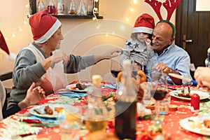Happy family having dinner at home in christmas - Grandfather holding his grandson - Holiday and togetherness - Joyful and new