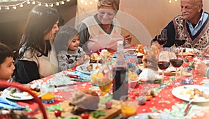 Happy family having dinner at home - holiday and togetherness near xmas tree - Focus on grandfather - joyful christmas eve