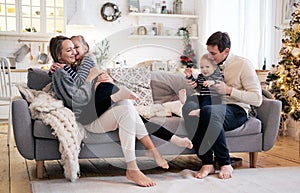 Happy family having fun in bedroom. Cheerful young family with kids sitting on sofa