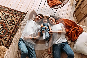 Happy family having fun in the bedroom while they lie on bed. Happy young family.