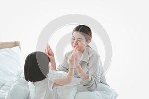 Happy family having fun in the bedroom. Mother, and daughter spending time together, little girl playing with her mom on bed,