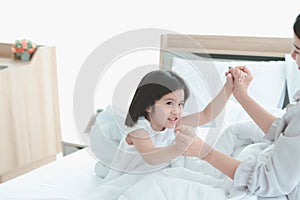 Happy family having fun in the bedroom. Mother, and daughter spending time together, little girl playing with her mom on bed,