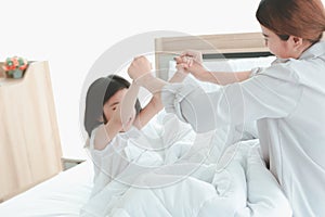 Happy family having fun in the bedroom. Mother, and daughter spending time together, little girl playing with her mom on bed,