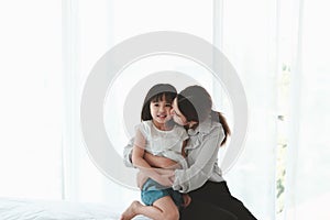 Happy family having fun in the bedroom. Mother, and daughter spending time together, little girl playing with her mom on bed,mom