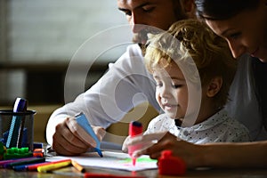 Happy family having fun draw together at a home, parents and little child playing together. Cheerful son with father and