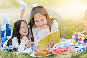 Happy family having fun and enjoying outdoor laying on picnic blanket reading book