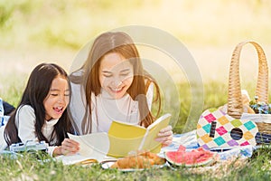 Happy family having fun and enjoying outdoor laying on picnic blanket reading book