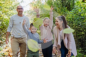 Happy family having fun with a foliage in autumn forest.