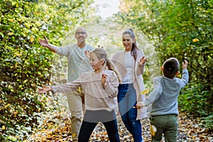 Happy family having fun with a foliage in autumn forest.