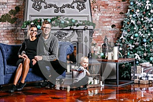 Happy family having fun at home. Christmas morning in loft room with brick wall. Young parents with little son. father