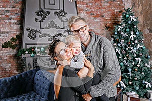 Happy family having fun at home. In loft room with brick wall. Young parents with little son. father, mother and their