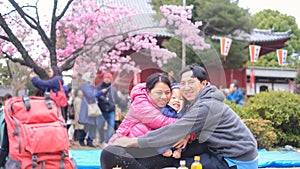 Happy family having fun outdoors in blossom spring public garden sightseeing sakura or cherry blossom in Tokyo, Japan