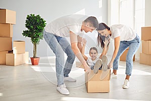 A happy family is having fun playing with a box on the floor in a new apartment.