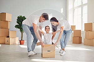 A happy family is having fun playing with a box on the floor in a new apartment.