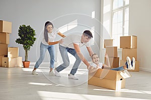 A happy family is having fun playing with a box on the floor in a new apartment.