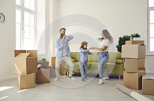 Happy family having fun in room with unpacked boxes in their new home on moving day