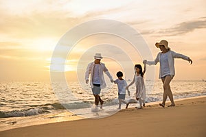 Happy family having fun running on a sandy beach at sunset time