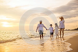 Happy family having fun running on a sandy beach at sunset time