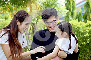 Happy family having fun and spending time together in summer green garden, father and mother playing with kid, dad carrying cute