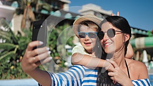 Happy family having fun taking selfie near swimming pool using smartphone close-up