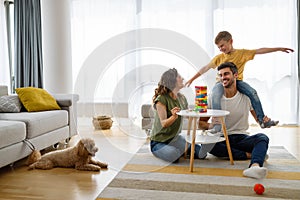 Happy family having fun time, playing together at home with dog