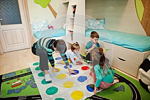 Happy family having fun together,four kids playing twister game at home