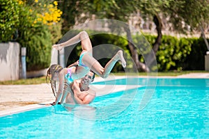 Happy family having fun together in outdoors swimming pool