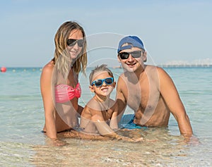 Happy family having fun on tropical white beach. Mother, father, a cute son. Positive human emotions, feelings, joy. Funny cute ch