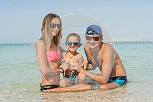 Happy family having fun on tropical white beach. Mother, father, a cute son. Positive human emotions, feelings, joy. Funny cute ch