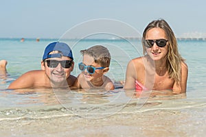 Happy family having fun on tropical white beach. Mother, father, a cute son. Positive human emotions, feelings, joy. Funny cute ch