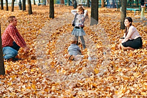 Happy family having holiday in autumn city park. Children and parents posing, smiling, playing and having fun. Bright yellow trees