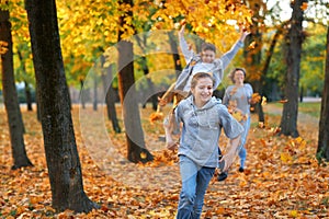 Happy family having holiday in autumn city park. Children and parents running, smiling, playing and having fun. Bright yellow