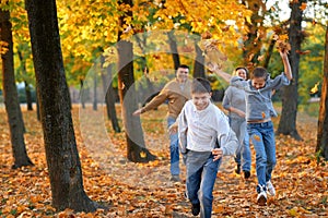 Happy family having holiday in autumn city park. Children and parents running, smiling, playing and having fun. Bright yellow