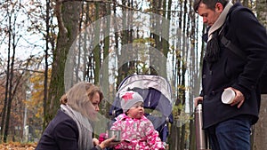 Happy family having picnic in autumn park. Pouring and drinking hot steaming tea from vacuum flask. 4K steadicam video